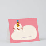 pink greetings card showing an illustration of a fluffy white cat lying down wearing a party hat