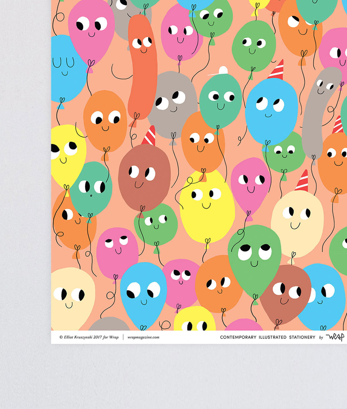 corner detail of fun birthday wrapping paper smiling balloons in different colours on a peach background