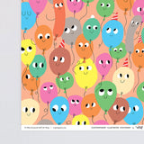 corner detail of fun birthday wrapping paper smiling balloons in different colours on a peach background