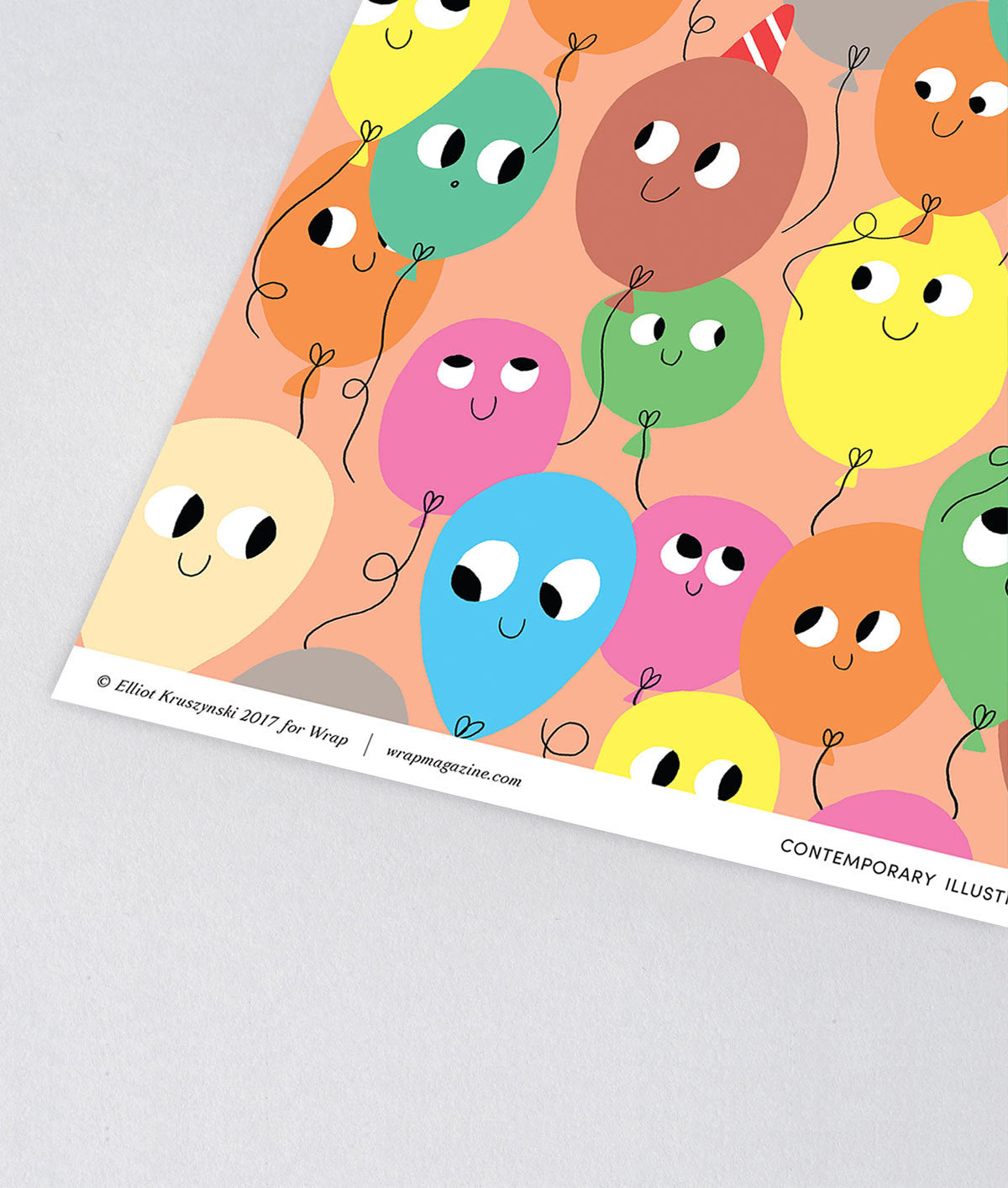 corner detail of fun birthday wrapping paper smiling balloons in different colours on a peach background