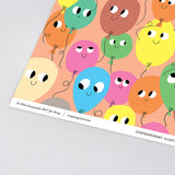 corner detail of fun birthday wrapping paper smiling balloons in different colours on a peach background