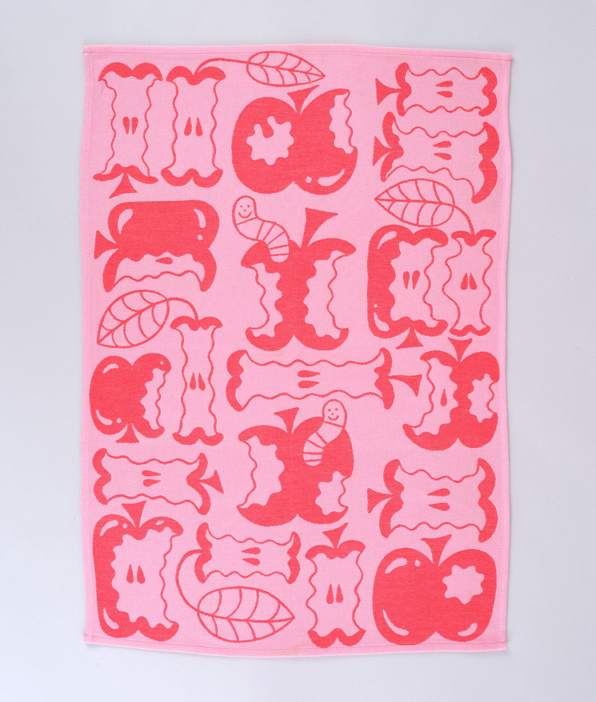 Full view of the pink apple a day tea towel featuring half eaten apples and cartoon worms