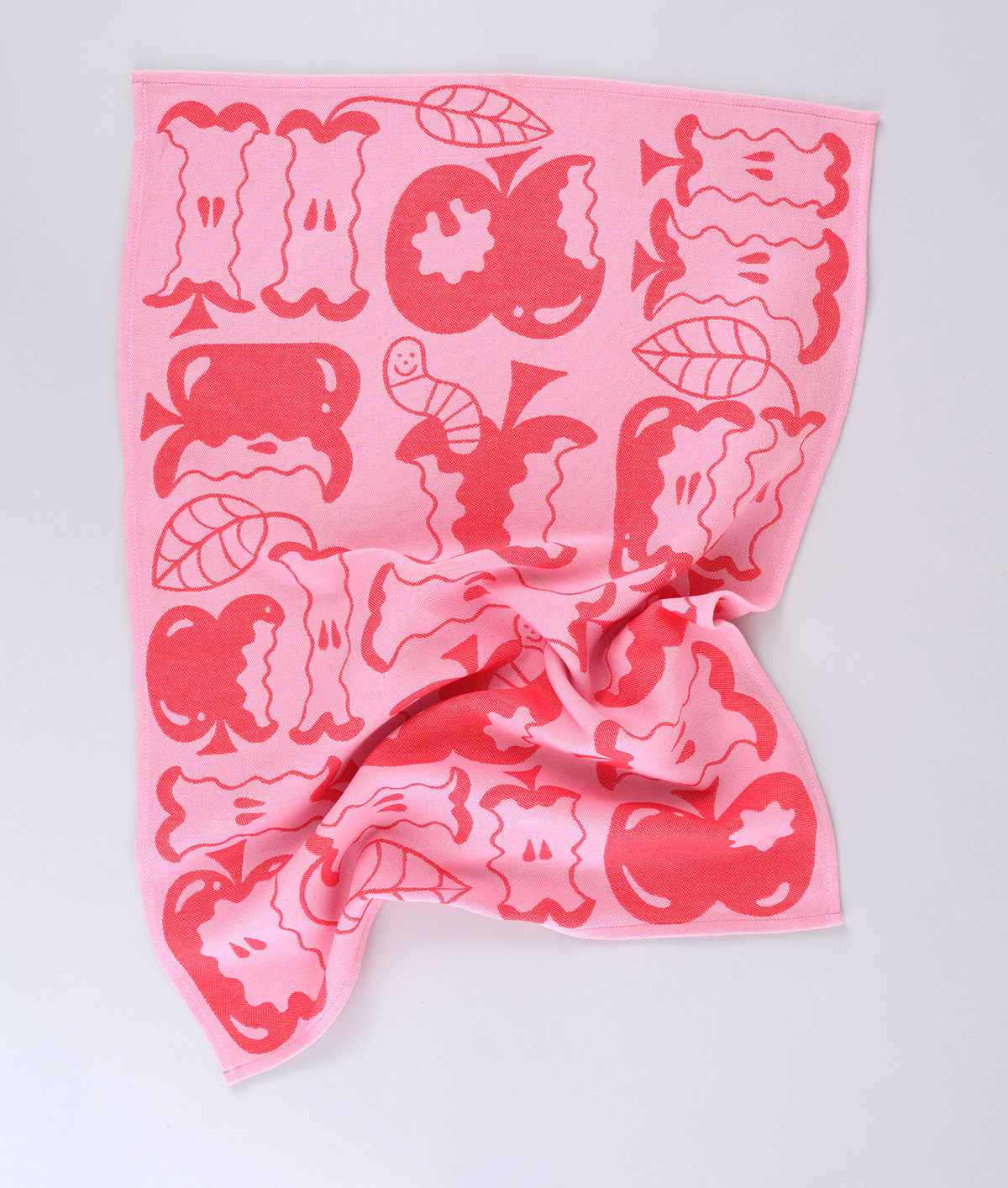 Full view of the pink apple a day tea towel featuring half eaten apples and cartoon worms