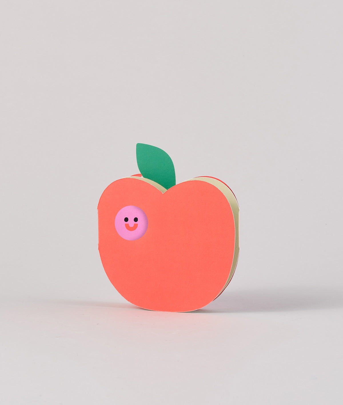 apple with worm die cut out card against a grey background