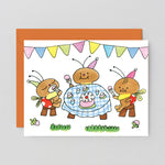 Greeting card with cartoon ants celebrating a birthday, featuring colorful flags and a cake.