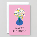 this pink birthday card shows a bunch of flowers in a blue vase and says Happy Birthday