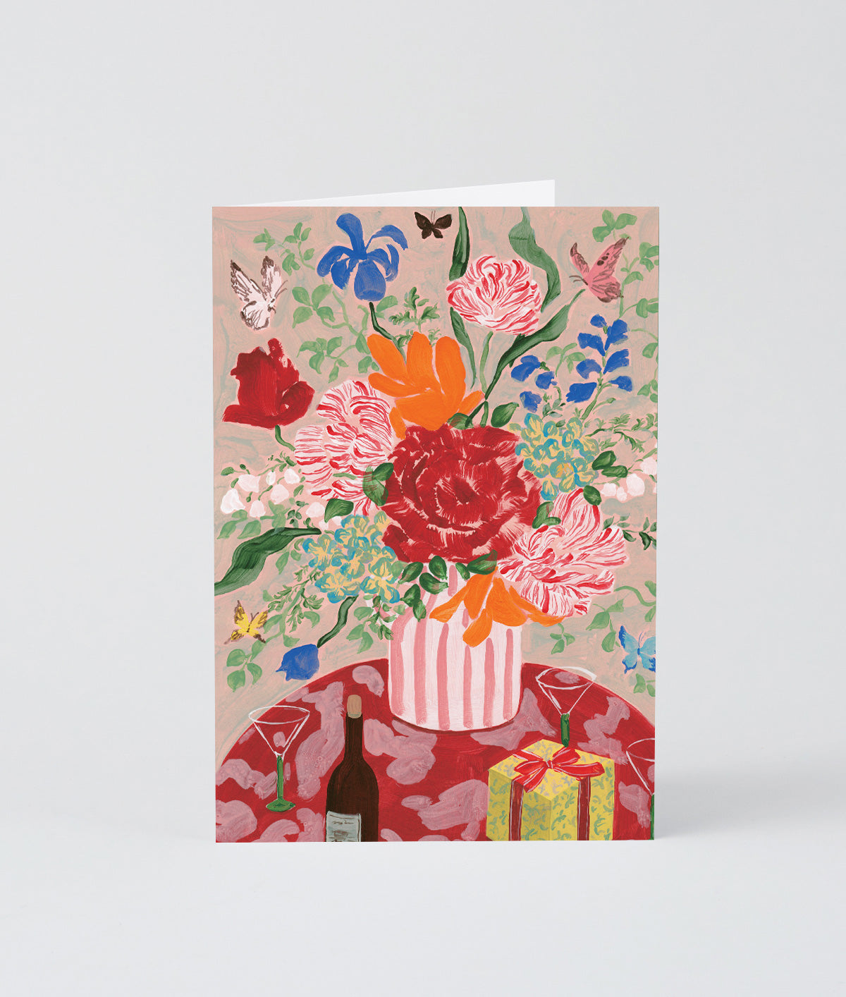 a bouquet of flowers and present on a greetings card against a grey background