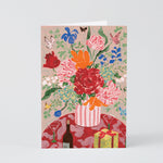 a bouquet of flowers and present on a greetings card against a grey background