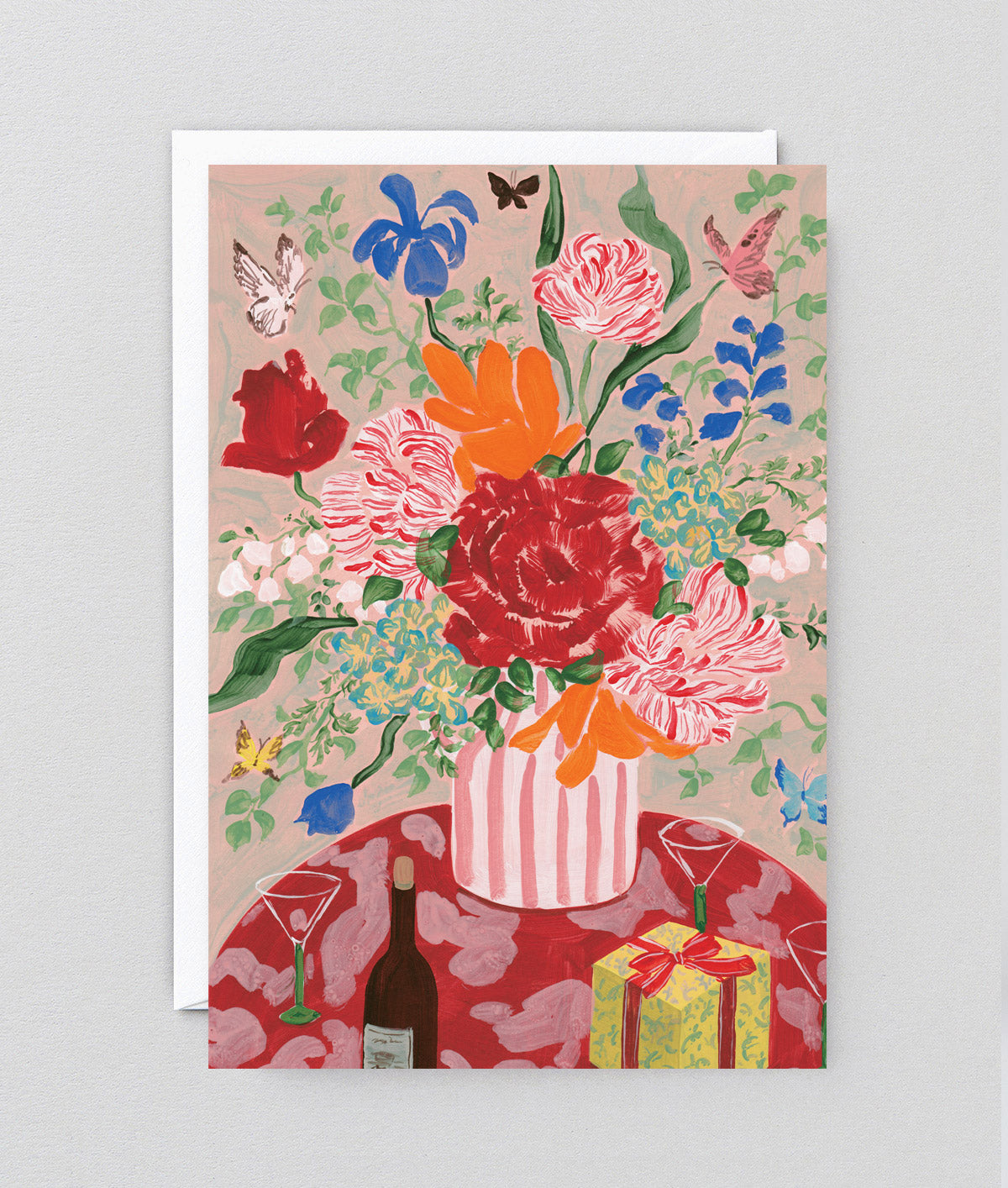 a bouquet of flowers and present on a greetings card and envelope against a grey background
